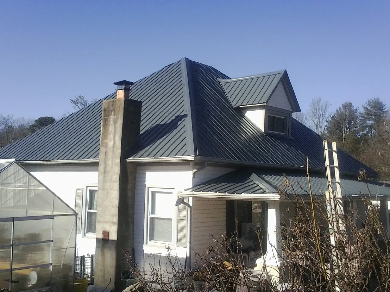Dark blue standing seam metal roof on a white farmhouse with dormer — Slate & Tile Roof Repair by Roofing Brothers in Tellico Plains