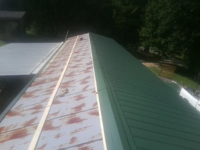 Old rusted panels beside newly installed green metal roofing — Wind Damage Roof Repair by Roofing Brothers in Tellico Plains