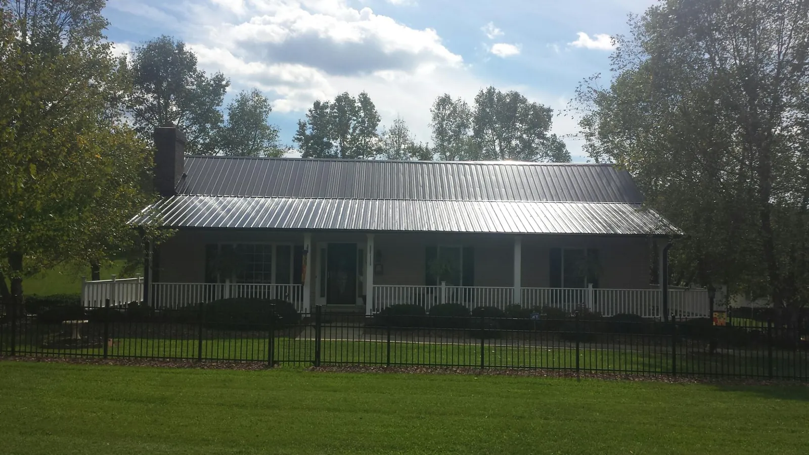 Gray metal roof on a brick ranch with a full width front porch — Gutter Guard Installation work by our crew in Tellico Plains