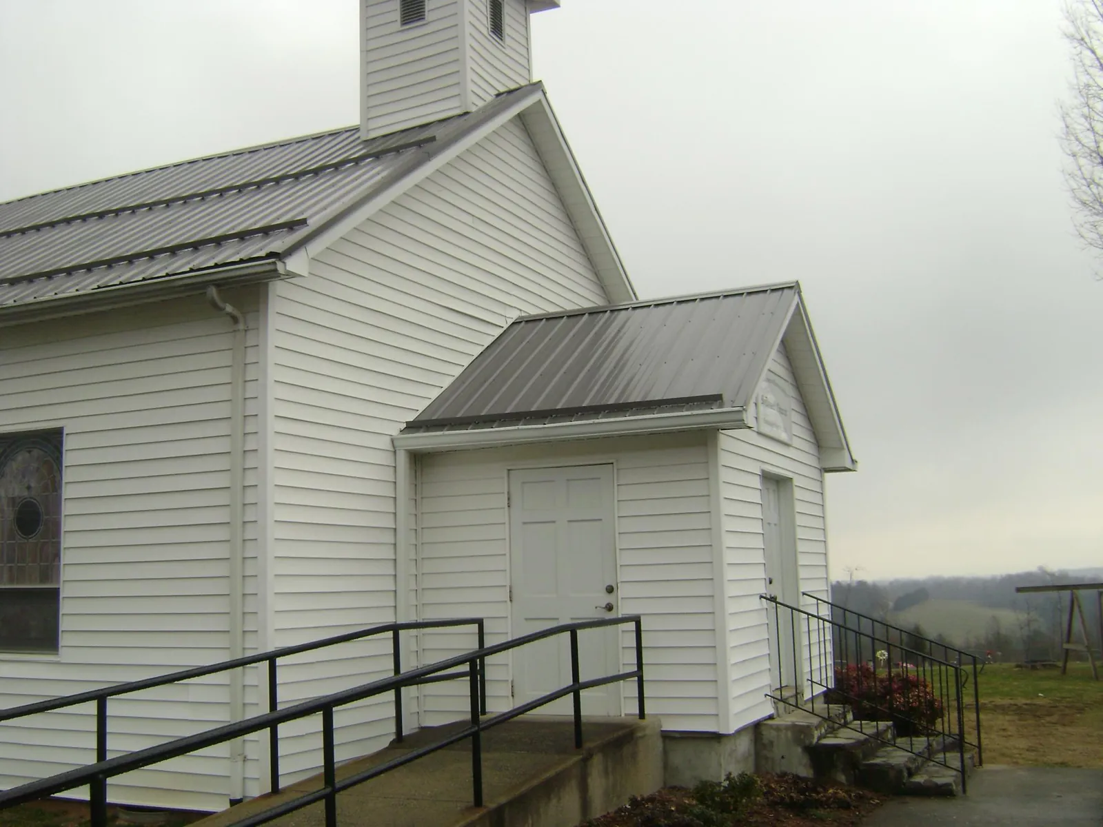 Gray metal roof on a white clapboard church with a steeple in Tellico Plains