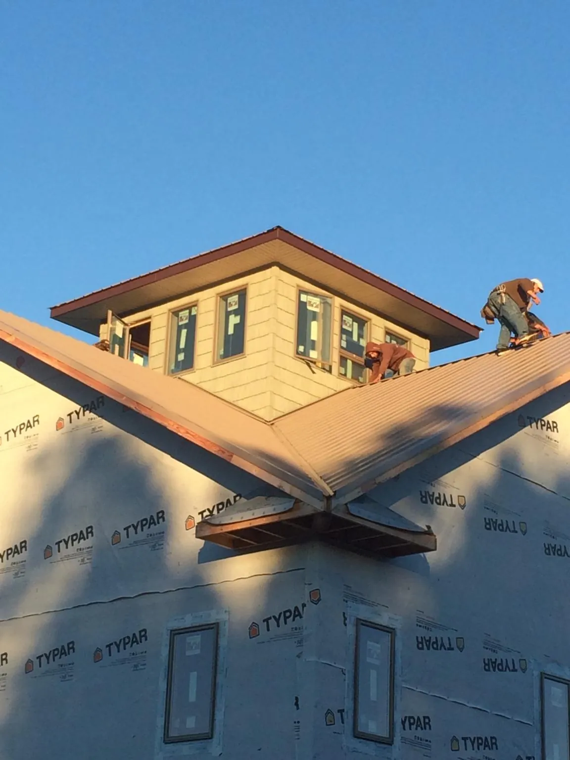 Roofers working around a rooftop cupola on a new metal roof at sunset — Roof Waterproofing in Tellico Plains by Roofing Brothers